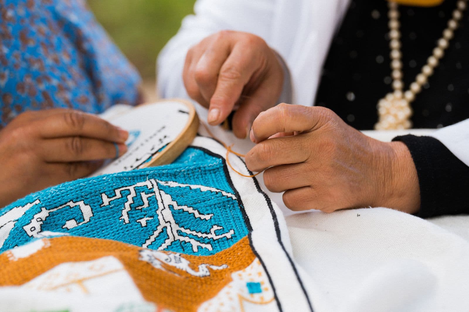 An artisan's hands mid-embroidery